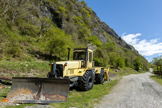 Yellow heavy duty wheeled tractor with a blade in the mountains