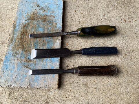 Three chisels rest on a worn wooden block. manual equipment.