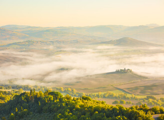 Obraz premium Hilly fields in the foggy valley after sunrise in autumn, Tuscany, Italy.