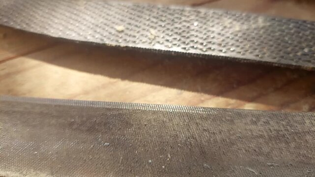 Close-up panning over various steel metalwork files and wood rasps on a workbench