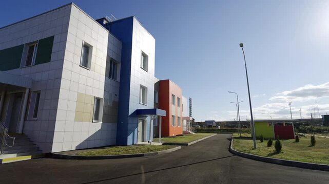 Clean tiled facade stands out against blue summer sky. Contemporary design reflects high quality standards of newly built school facility