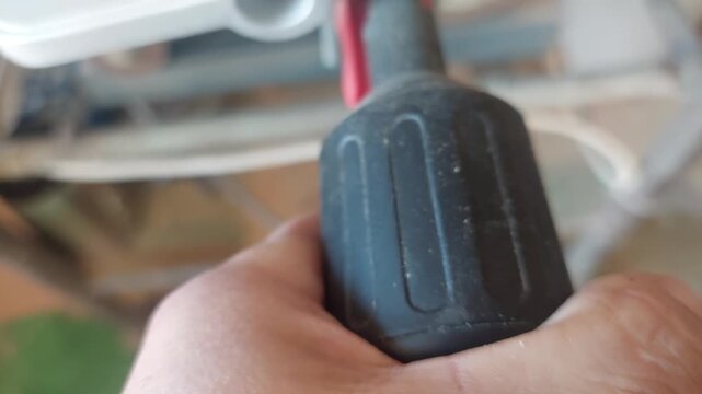 Hand turning a black plastic textured adjustment knob on a workshop machine