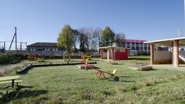 Vibrant playground structures stand on lush green grass field. Slides and swings around pavilions offer diverse fun for active children