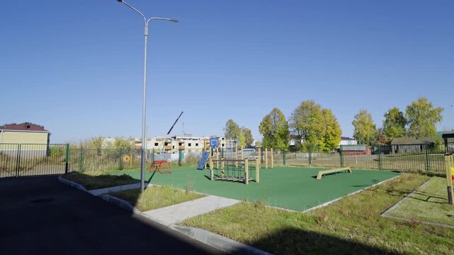 Playground stands next to green rubberized athletic zone. Functional outdoor space supports active physical education and creative play