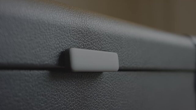 Close-up view of a textured black storage box with a gray handle, showcasing the gradual reveal of the handle in a well-lit indoor setting