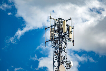 Telecommunications cell tower under blue sky with clouds. Low angle view of a modern...