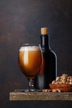 Beer glass with foam and bottle with pistachios