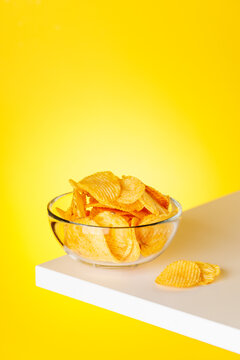 Bowl of potato chips on yellow background minimal snack composition