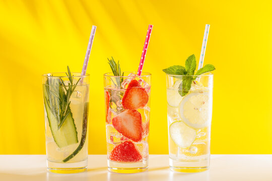 Set of fresh non alcoholic drinks with strawberry cucumber and lemon on yellow background