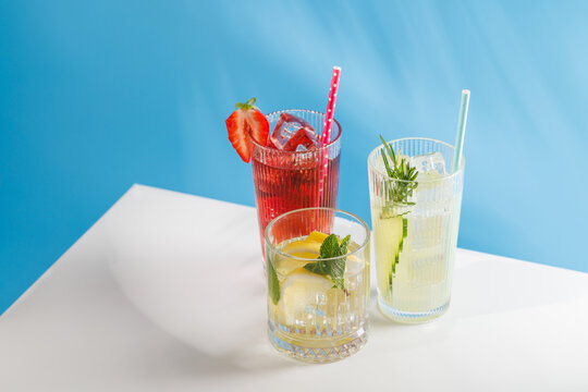 Assortment of non alcoholic refreshing drinks with herbs and citrus on blue background