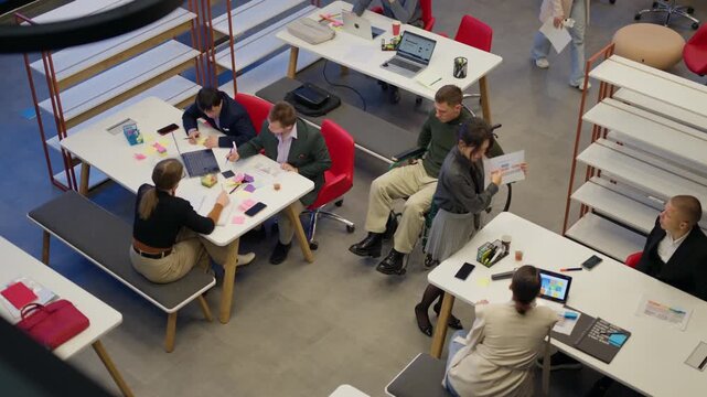Diverse professionals collaborate and work together in a modern open-plan office environment. A team of colleagues, including a man in a wheelchair, engages in productive office tasks.