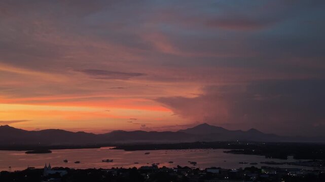 Sunset storm sky over Puerto Princesa City bay with rain clouds mountain silhouettes and distant heat lightning glow in Palawan Philippines