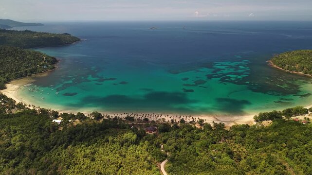 High aerial view of turquoise bay reef patches forested beach and tropical shoreline in Bacungan Palawan Philippines