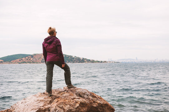Adventure woman standing on rocky coastline inspires travel lifestyle