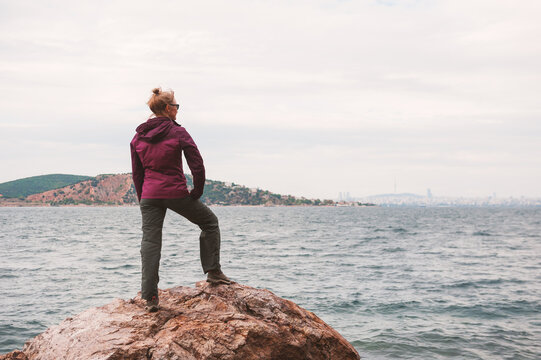 Adventure woman standing back on rocky coastline