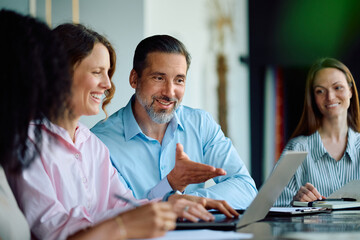 Fototapeta premium Happy coworkers using laptop during business meeting in office.