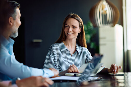 Happy entrepreneur talking to her colleagues during business meeting in office.