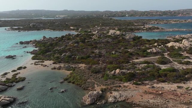 Breathtaking aerial view flying over the rocky coastline of the La Maddalena archipelago, revealing its stunning turquoise waters in Sardinia