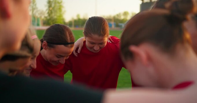 Women's soccer team in red jerseys gathers in a tight pregame huddle on the field, sharing focus, unity, and encouragement before competition