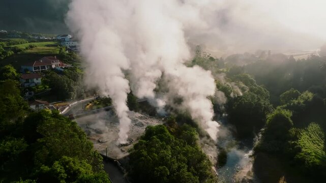 A person standing with a child at a viewpoint overlooking geothermal fumaroles in Furnas, Sao Miguel Island, with plumes of volcanic steam rising against a mountainous, misty backdrop.