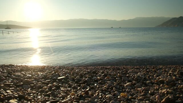 Calm lake sunrise with rocky shore and mountains