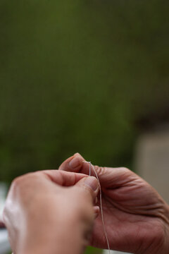 Vertical close up of senior woman threading sewing needle