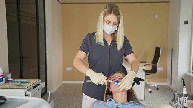 Dentist using ultraviolet curing light during dental procedure on patient in clinic. Concept of dental treatment and modern dentistry.