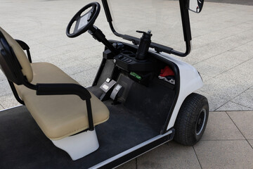 White electric golf cart parked on a modern outdoor pedestrian plaza near the seaside © Светлана Высокос
