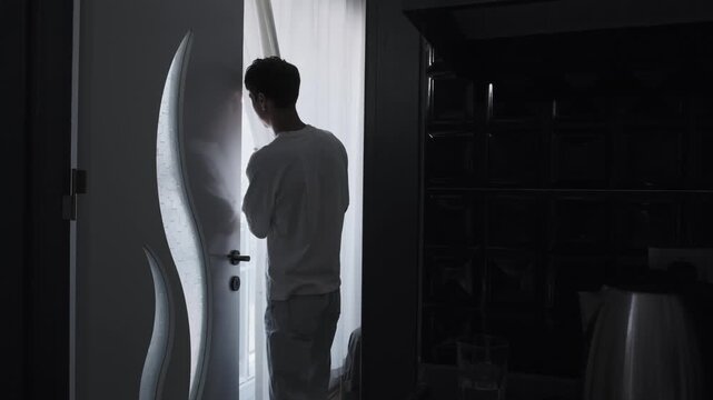 Paranoia and persecution mania concept with anxious man secretly looking through curtain, psychological fear, surveillance suspicion and unsafe home atmosphere