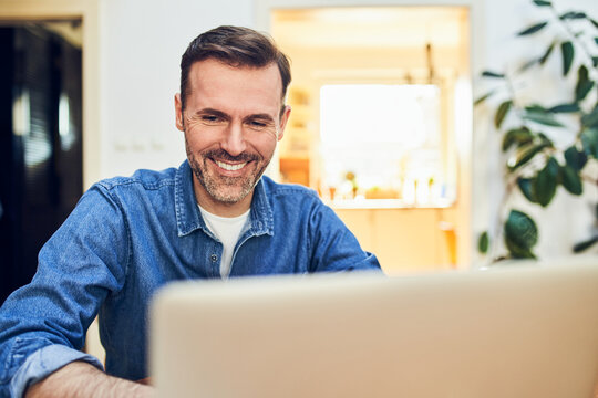 Man smiling while using laptop at home
