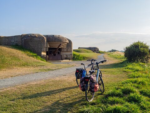 Batterie de Longues-sur-Mer, dos bicicletas en el campo de batalla de la segunda guerra mundial en normand&iacute;a con artiller&iacute;a original, protegida por construcciones de hormig&oacute;n, viajando en verano 2022