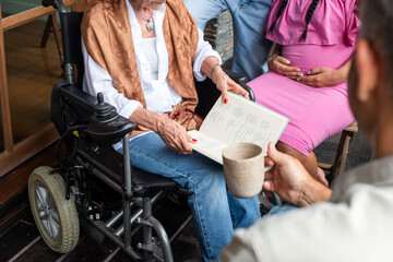 Group of people, one in a wheelchair, reading a menu outdoors.