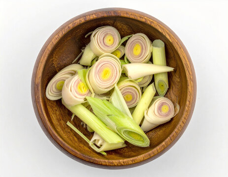 Portion of cut lemongrass in a wooden pot, seen from above, on a white background.