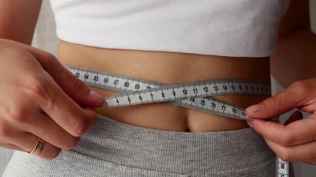 Woman tracking body shape and weight loss progress at home.