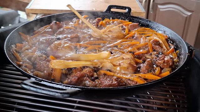 Steaming hot plov pilaf cooking in cast iron kazan with lamb, carrot, onion, garlic and spice on outdoor grill. Traditional Uzbek recipe.
