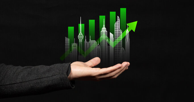 A modern businessman hand holding a real estate profits concept with a graph a skyscrapers line and an arrow