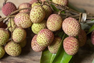 Fototapeta premium Fresh lychee fruit cluster on rustic wooden background