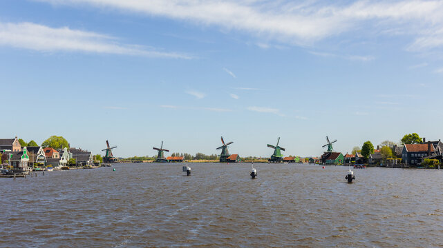 Windmills at Zaanse Schans while exploring the Dutch countryside by the canals in the Netherlands.