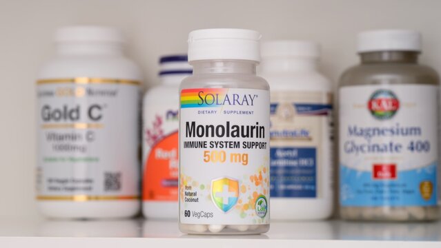 Tambov, Russian Federation - February 19, 2022 Bottle of Solaray Monolaurin dietary supplement capsules standing on a shelf with other supplement jars.