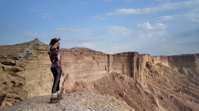 woman tourist looking the edge of the world escarpment at sunset, contemplating the cliffs of Tuwaiq mountain range in Riyadh, Saudi Arabia