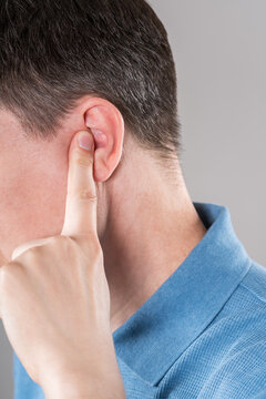 Man with earache on gray background, ear pain and otitis
