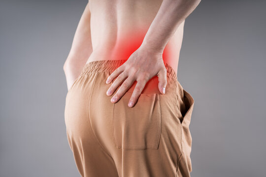 Man suffering from kidney pain and holding lower back with red spot highlighting inflammation. Renal disease, kidney stones and backache medical concept