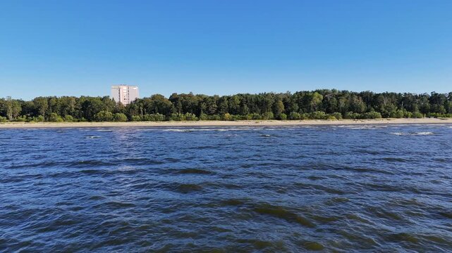 Aerial drone view of Jurmala beach and Lielupe river, Latvia. Baltic sea coast bordered by dense green pine forests.