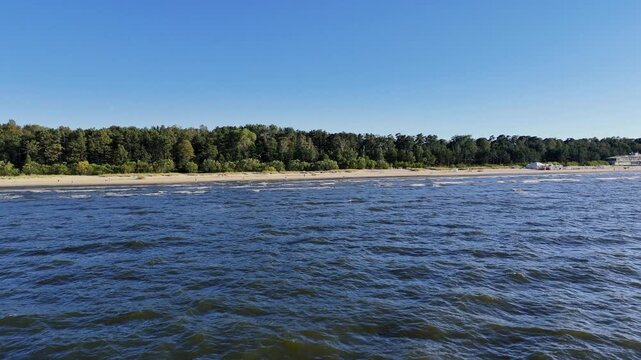 Aerial drone view of Jurmala beach and Lielupe river, Latvia. Baltic sea coast bordered by dense green pine forests.