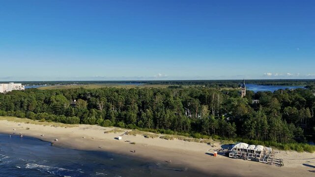 Aerial drone view of Jurmala beach and Lielupe river, Latvia. Baltic sea coast bordered by dense green pine forests.