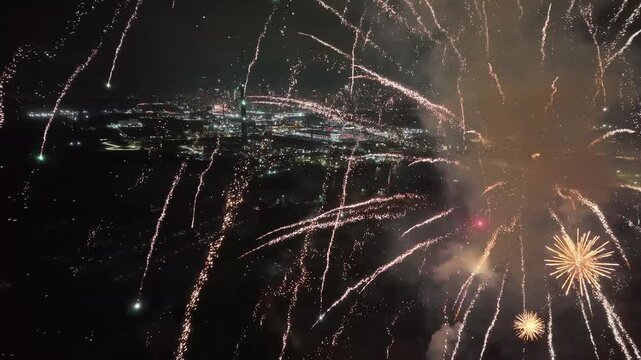 Aerial camera pushes forward into a spectacular barrage of golden sparks and fireworks, framing a panoramic night view of the glowing Toronto cityscape below