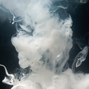 White smoke rising in a dark background creating patterns of swirls and shapes