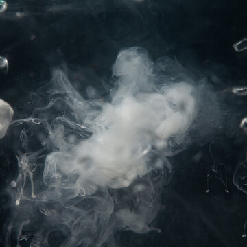 White smoke curls against a dark backdrop, forming unique shapes and patterns that slowly rise upwards