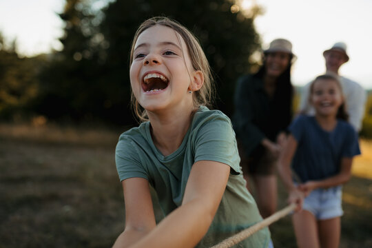 Family playing tug of war together outdoors during fun summer day.