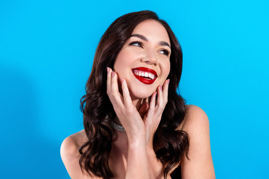 Smiling woman portrait with red lipstick and glamorous jewelry against bright blue background, joyful beauty and fashion look